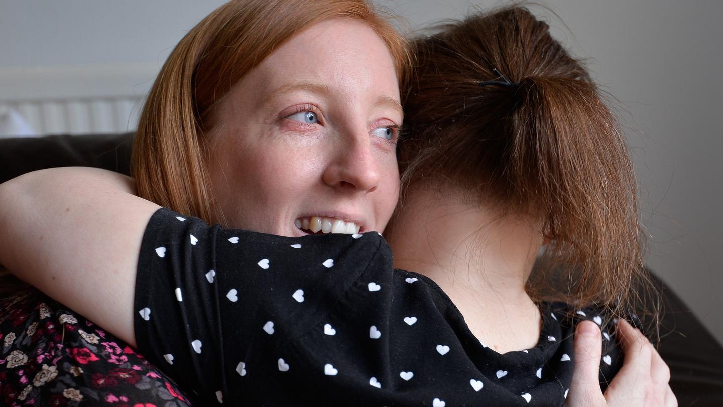 A UK carer being hugged by the young lady she cares for.