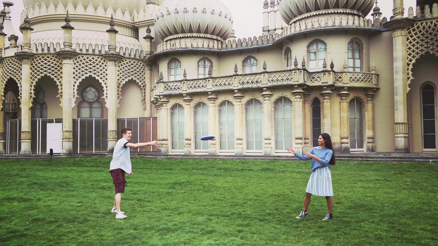 Taz and Danny, who work at the FatFace Brighton store, playing frisbee in their FatFace clothes outside the Royal Pavilion