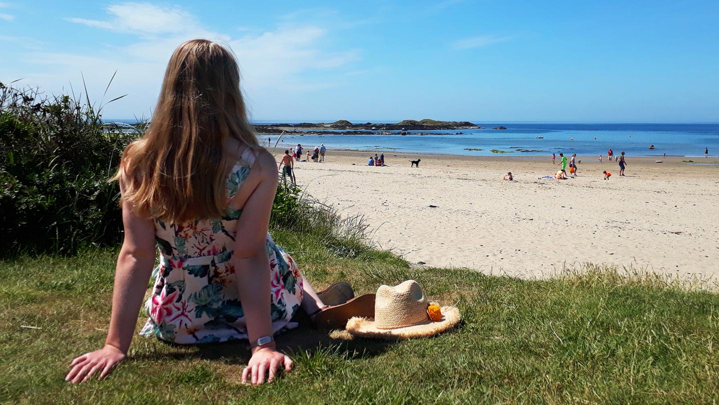 A FatFace crew member from Rhosneigr, chilling on the beach in the Serena Tropical Dress from FatFace