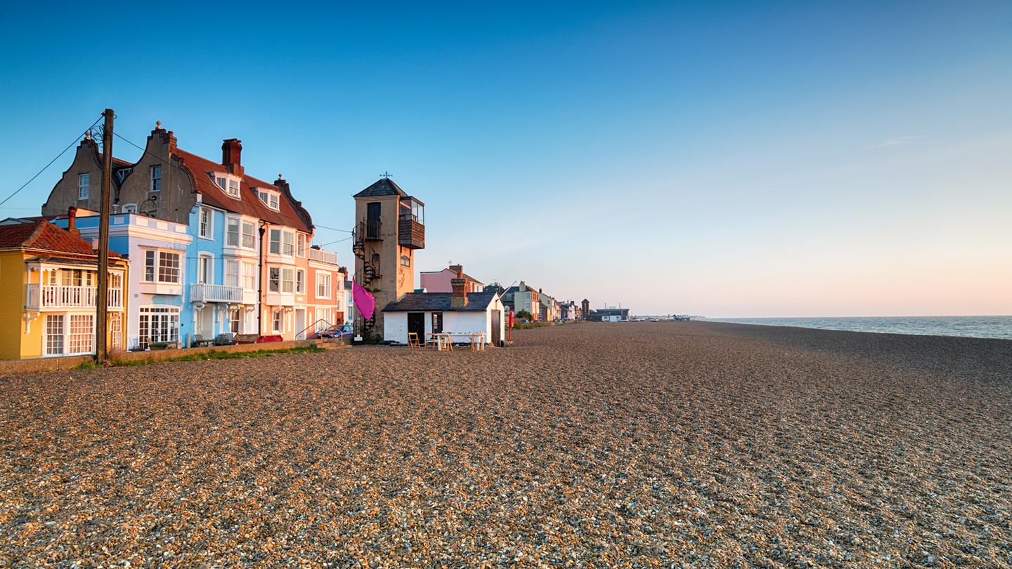 A beautiful scene of the beach at Aldeburgh, with pastel coloured buildings and sand and shingle