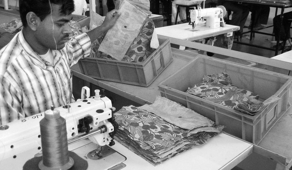 A factory worker organises fabric around a sewing machine.