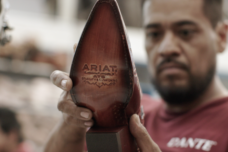 Man holding and looking at an Ariat boot