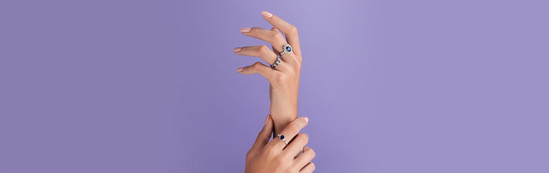 Elegant hands wearing three sapphire and diamond rings