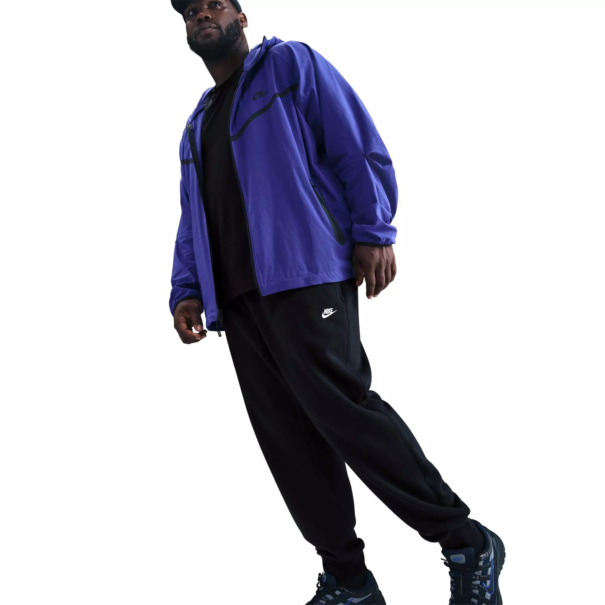 Side view of man wearing black Nike Club Joggers with purple jacket demonstrating casual layering style