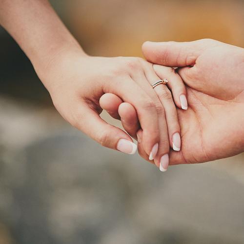 man holding woman's hand with engagement ring on